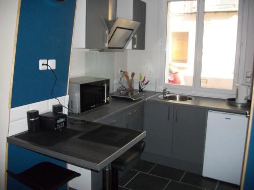 a small kitchen with a sink and a microwave at Les Mouettes in Le Tréport