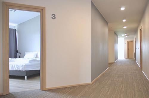 a hallway leading to a bedroom with a bed and a mirror at Lilja Guesthouse in Höfn