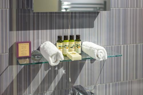 a glass shelf with oils and towels on a wall at Lulworth Lodge in Lulworth Cove