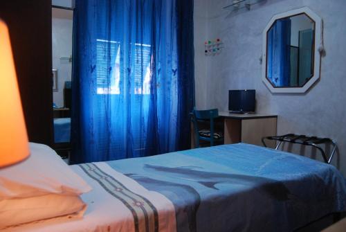 a bedroom with a bed with blue curtains and a mirror at Casa MaMa Guesthouse in Genova