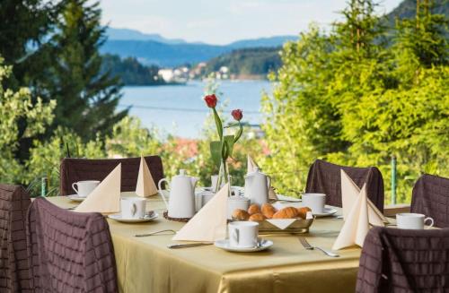 a dining table with a view of a lake at Hotel Faaker See Inn by S4Y in Faak am See