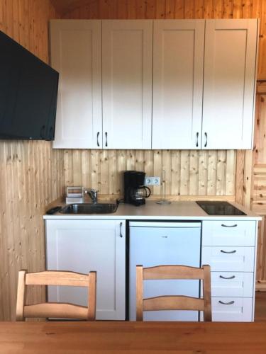 a kitchen with white cabinets and two chairs at Hekla Adventures in Hvolsvöllur