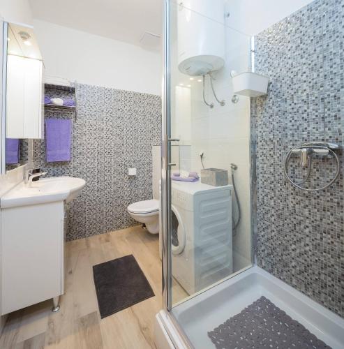 a bathroom with a shower and a toilet and a sink at Apartmani Ujakovic in Kaštela