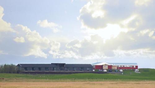 a building in a field with a cloudy sky at Lilja Guesthouse in Höfn