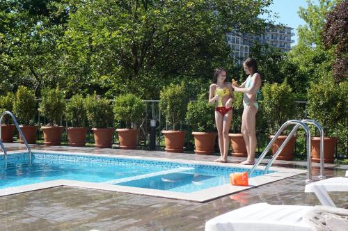 two girls are standing on the edge of a swimming pool at Gold Guest House in Gonio