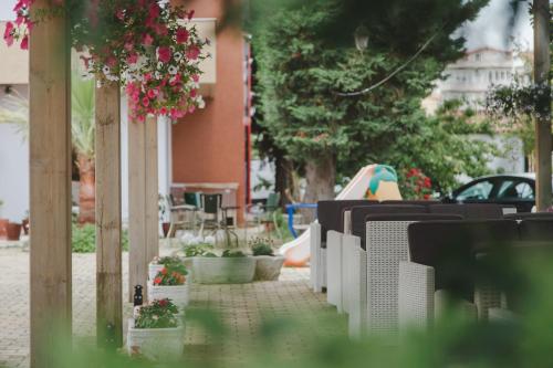 a row of tables and chairs on a sidewalk with flowers at Kadrisa Hotel in Durrës