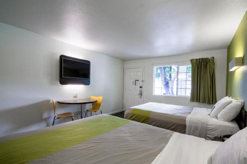a hotel room with two beds and a table and a tv at Fisherman's Cove Inn in Monterey