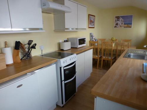 uma cozinha com armários brancos e um forno com placa de fogão em The Dales em Stanhope