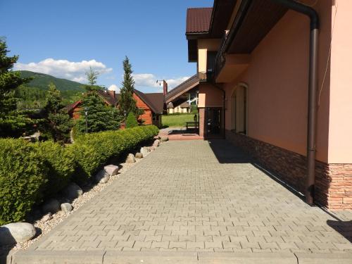 a brick walkway next to a building with a driveway at Penzion Montana in Terchová