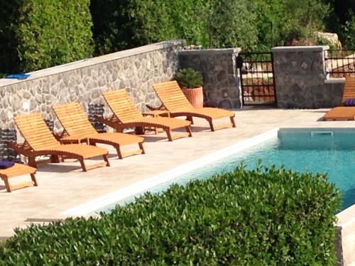 a group of chairs sitting next to a swimming pool at Apartments Vunić in Mošćenička Draga