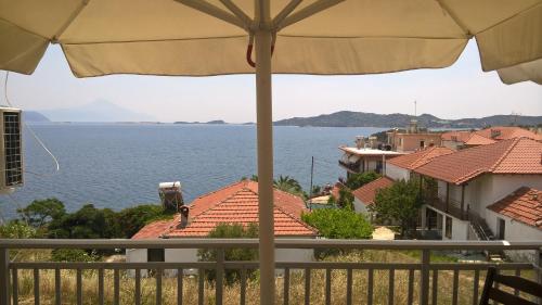 uma vista para o oceano a partir de uma varanda com um guarda-sol em Villa Elli em Amoliani