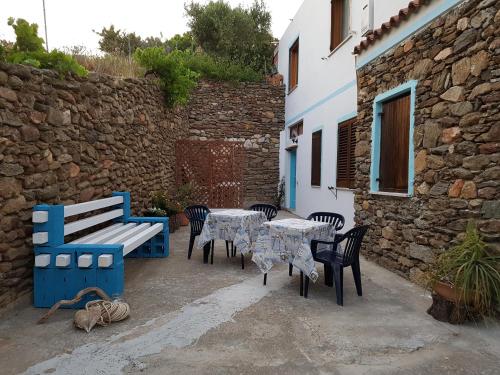 a patio with tables and chairs and a stone wall at Su Sole in Posada