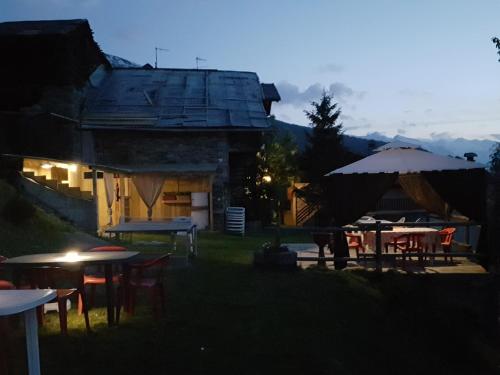 eine Gruppe von Tischen und Sonnenschirmen vor einem Gebäude in der Unterkunft Casa Chamonin in Gressan