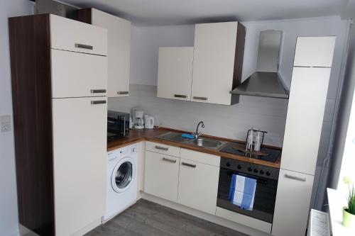 Scheuerfeld的住宿－Ferienwohnung Pecere，厨房配有白色橱柜、洗衣机和烘干机