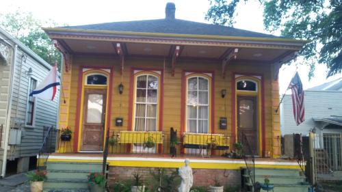 a yellow house with a front porch with chairs at Creole Victorian for groups large and small in New Orleans