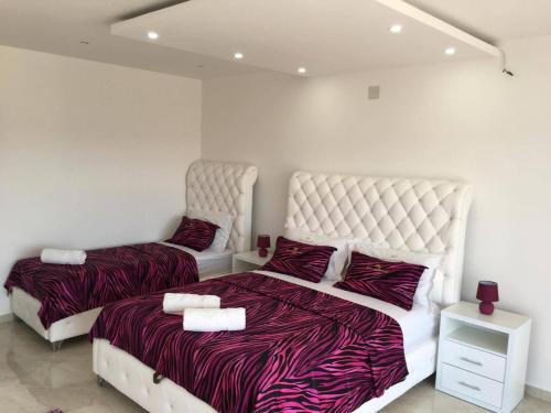 two beds in a room with white walls at Queen Kodre Apartments in Ulcinj