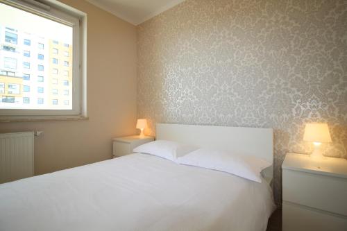 a bedroom with a white bed and a window at Sea Apartment in Gdańsk