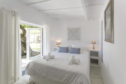 a white bedroom with a white bed and a window at O Moinho da Roca in Azoia