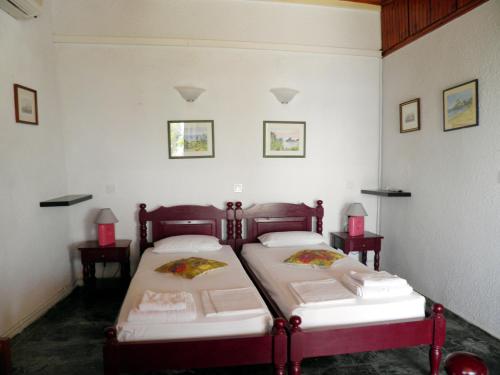two beds in a room with white walls at Akis Apartments Kontogialos-Pelekas in Pelekas