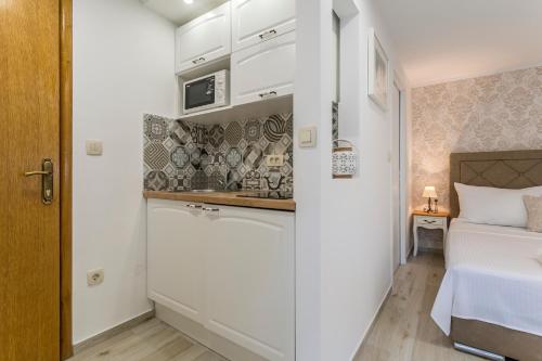 a small kitchen with white cabinets and a bed in a room at Split Center Apartments in Split
