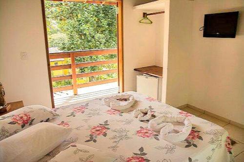 a bedroom with a bed with a floral bedspread and a window at Pousada Sol da Trindade in Trindade