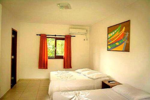 a bedroom with two beds and a window with red curtains at Pousada Sol da Trindade in Trindade