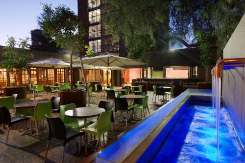 restauracja ze stołami i krzesłami oraz basen w obiekcie Hotel 224 & Apartments w mieście Pretoria