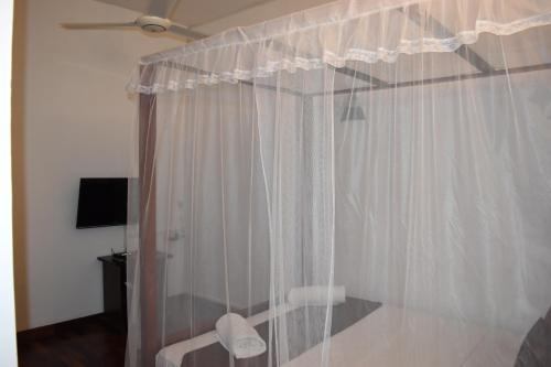 a bedroom with a white shower curtain and a fan at Cirute' Talwatte, Kandy in Kandy