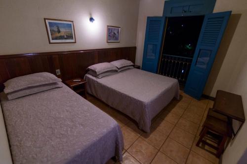 two beds in a hotel room with blue doors at Pousada do Canto in Rio Acima