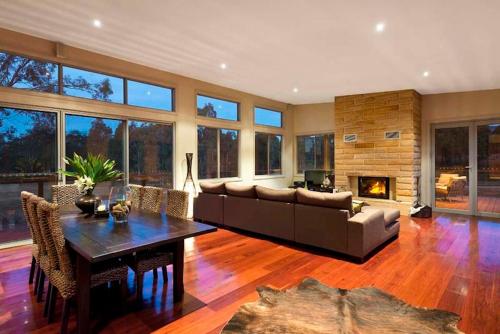 a living room with a couch and a table and a fireplace at Blue Cliff Retreat in Pokolbin