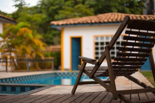 a wooden chair sitting on a deck next to a pool at Pousada do Canto in Rio Acima