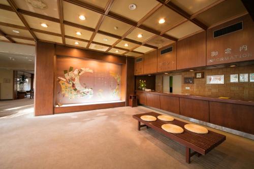 a lobby with a bench and a large painting at Ryokan Seishounagon in Tsu