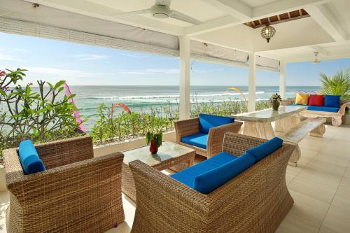 un patio al aire libre con sillas, una mesa y el océano en The Point Beach-Front Balangan, en Jimbaran