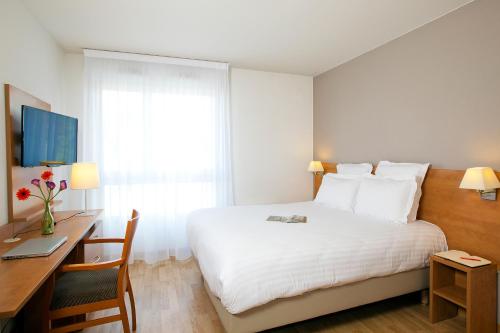 a hotel room with a bed and a desk and a computer at Séjours & Affaires Angers Atrium in Angers