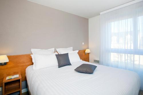 a bedroom with a large white bed with a window at Séjours & Affaires Angers Atrium in Angers