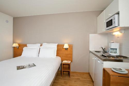 ein Hotelzimmer mit einem Bett und einer Küche in der Unterkunft Séjours & Affaires Angers Atrium in Angers