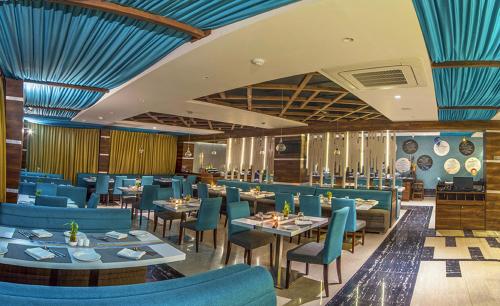a dining room with blue chairs and tables at The Fern Residency Kolkata in Kolkata