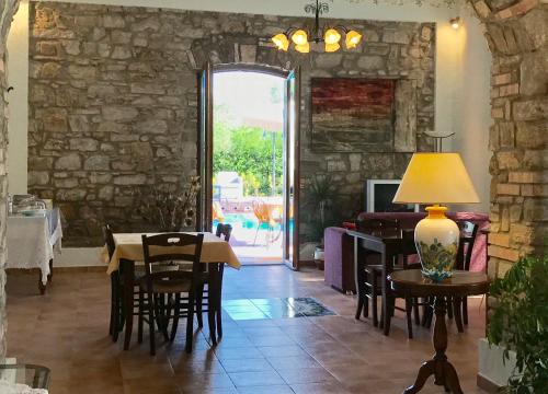 a dining room with a table and chairs and a room with a stone wall at Casa Vacanze Il Cenito in Castellabate