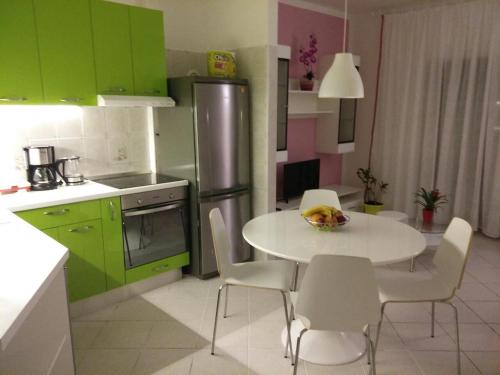 eine Küche mit grünen Schränken sowie einem weißen Tisch und Stühlen in der Unterkunft Apartman Gabi in Kastav