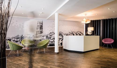 a room with chairs and a table and a wall at Hotel Alpha in Fribourg