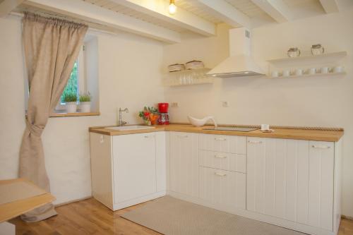 a kitchen with white cabinets and a sink and a window at Apartman Brunela-free parking in Šibenik