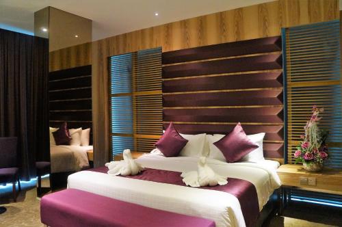 a bedroom with a large bed with purple pillows at Greens Hotel & Suites in Bintulu