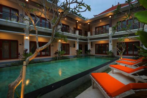 a swimming pool in front of a house with orange chairs at Avisara Villa & Suite in Nusa Dua
