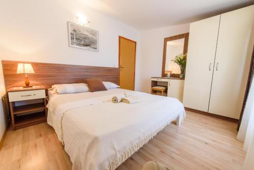 1 dormitorio con 1 cama blanca grande y cabecero de madera en Apartments Petra, en Marina