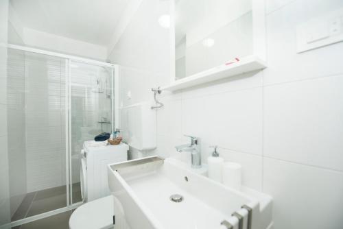 a white bathroom with a sink and a toilet at Maritimo Apartment in Split