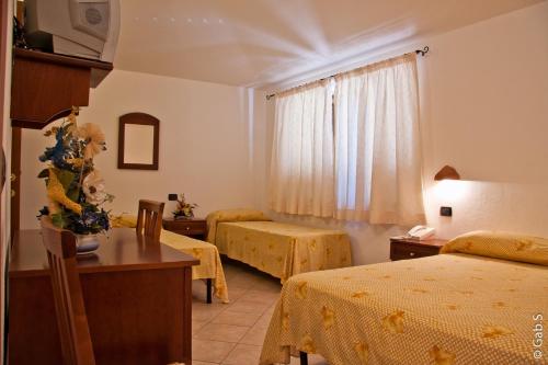 a hotel room with two beds and a table and chairs at Hotel Alador in Budoni