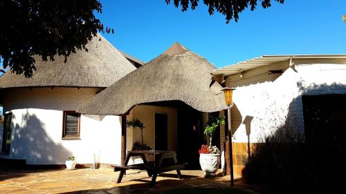 a white house with a thatched roof and a table at The Hut in Burgersdorp
