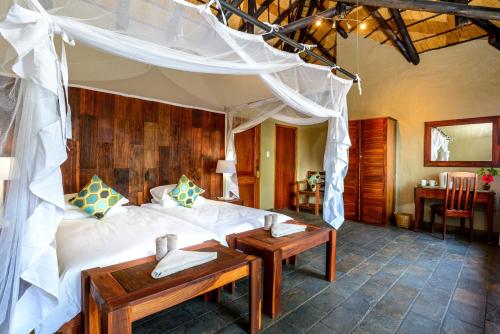 ein Schlafzimmer mit einem Bett und einem Tisch in einem Zimmer in der Unterkunft Gondwana Namushasha River Lodge in Kongola
