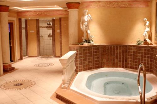 baño con bañera de hidromasaje y estatua en Hotel Keindl, en Oberaudorf