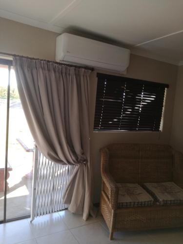 a room with a bed and a window with a fan at Elim Guesthouse in Keimoes